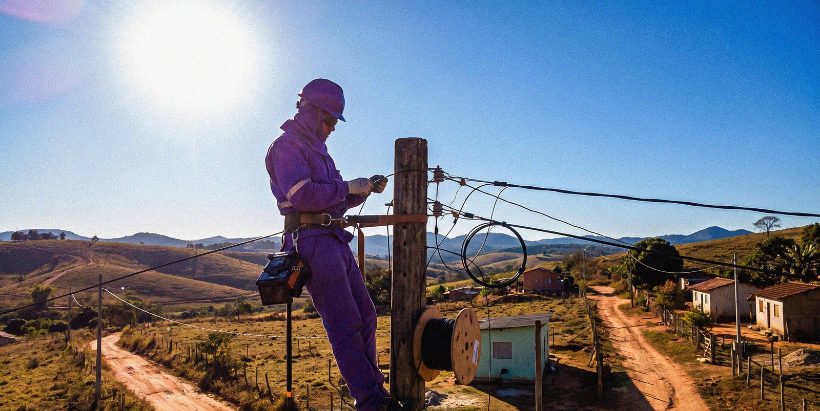 Técnico instalando cabo de fibra óptica em poste na zona rural de Rodeiro